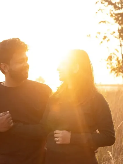 Holding hands and sharing a look in the warm, golden light. This simple, classic pose is all about their connection, framed by the beautiful, sunlit natural surroundings.