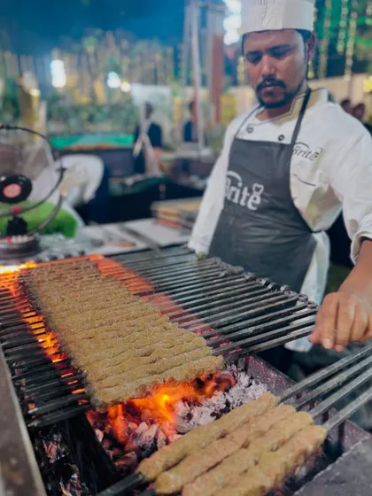 A chef's focused expression as he grills mutton seekh kebabs, highlighting our team's professionalism and skill.