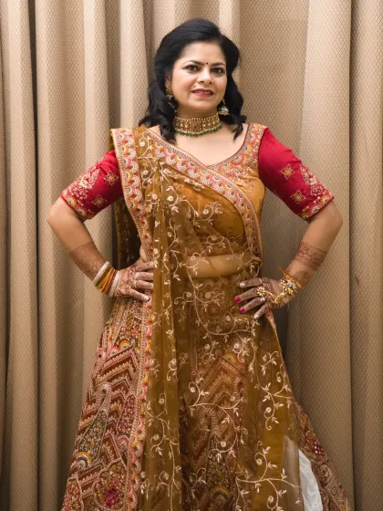 A full-length shot of the heavy bridal-style lehenga. The hands-on-hips pose is strong and classic for fashion photography.