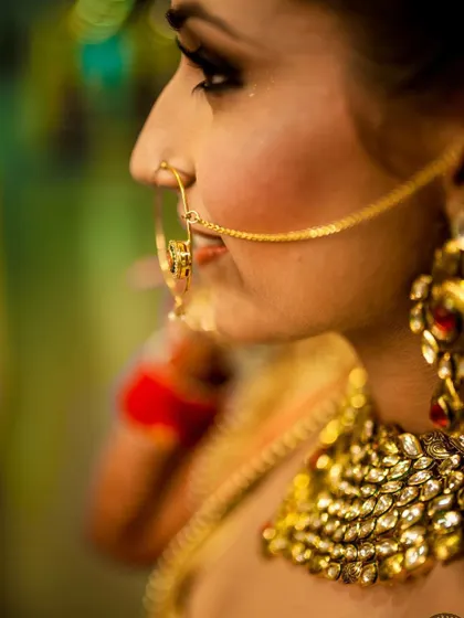 A detailed profile shot focusing on the bride's traditional nose ring and kundan necklace. I use a 35mm art lens to get close and capture the fine craftsmanship of the jewelry and the subtle expression of the bride.