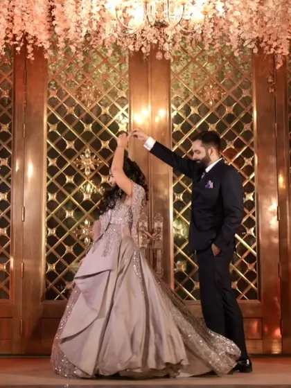 A beautiful moment of the couple dancing at their reception. The groom twirls the bride in front of a grand, golden doorway, creating a fairytale-like scene.