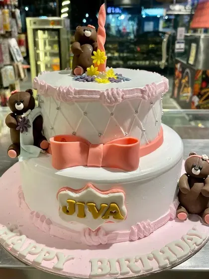 A sweet two-tier teddy bear cake for a little one's birthday. This design features a quilted pattern, a delicate pink bow, and cute chocolate bears.