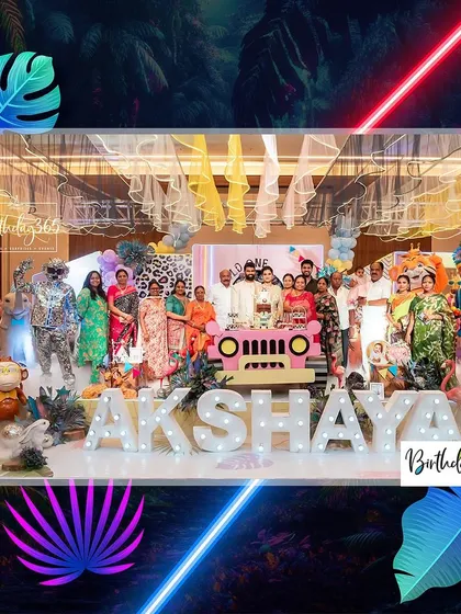 The whole family gathers for a photo at the neon jungle party. This wide shot shows the scale of the decor, with numerous animal props and a large, lighted name sign.