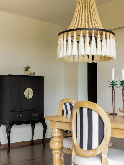 A dining space from 2023 with a bold, coastal-inspired beaded chandelier and classic striped chairs.