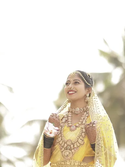 The bride looking up with a happy smile, her traditional jewelry and custom outfit creating a stunning bridal look.