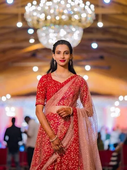 For this client attending her brother's engagement, we chose a sophisticated and elegant look. The makeup features a classic red lip and defined eyes, paired with soft, side-parted hair that beautifully complements her stunning red lehenga.