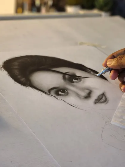 A work-in-progress shot showing my hand using a precision eraser to add highlights to the face.