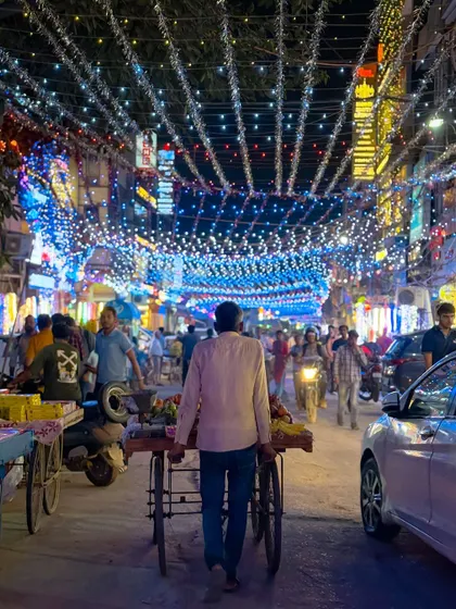 The streets of Delhi illuminated with strings of lights for Diwali. This image captures the festive hustle and bustle as people shop and celebrate.