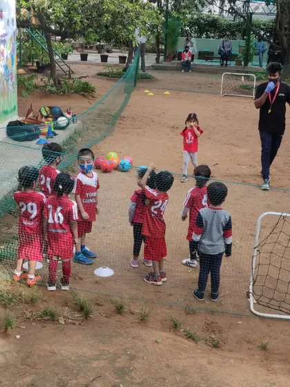 A coach gives instructions to a group of young players, some wearing masks, showing our commitment to safety.