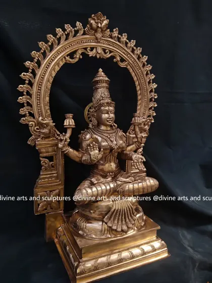 A 23-inch MahaLakshmi sculpture, seated on a throne and framed by a beautifully carved Prabhavali arch. This Panchaloha piece radiates divine grace and is a symbol of auspiciousness and prosperity.