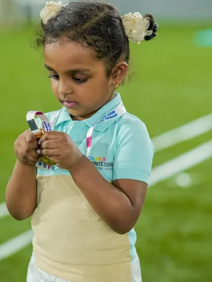 A young athlete proudly examines her medal, a tangible reward for her effort and participation.