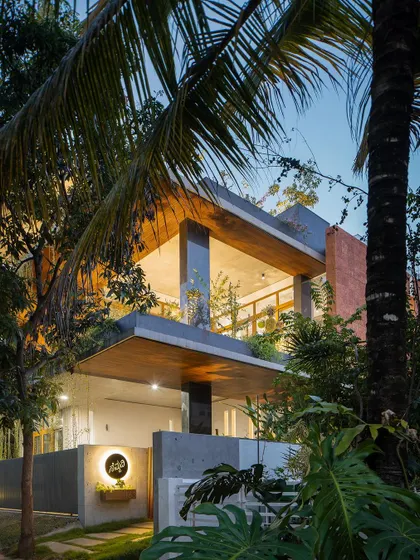 A duplicate image of the house at dusk, highlighting the warm lighting and lush greenery.