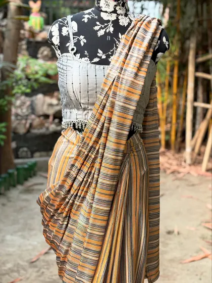 A close-up of the draped striped saree, showing the texture of the fabric and the detailed tassels on the blouse.
