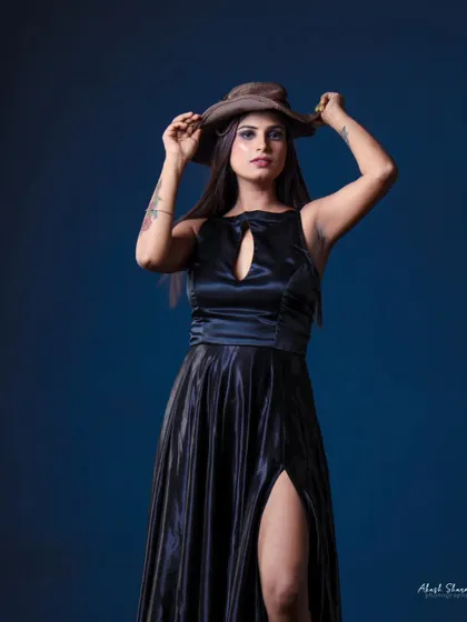 A full-body shot of the model in the black gown against a blue backdrop. The contrast in colors makes the outfit pop.
