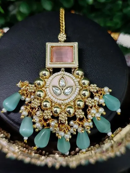 A detailed view of a maang tikka with pastel pink and mint green accents, perfect for a modern, daytime wedding.
