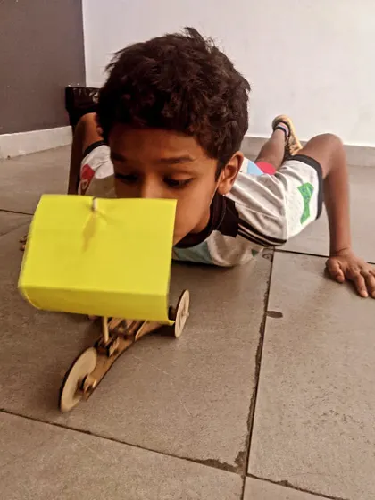 A student tests his wind-powered sail car on the floor. This is a fun way to learn about aerodynamics and energy transfer.
