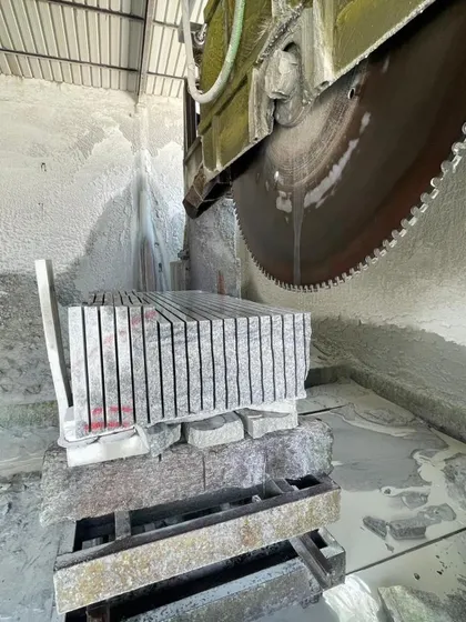 A large circular saw cutting through a stack of granite slabs in my workshop.