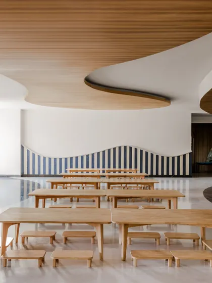 A multi-purpose hall at Vedanya School with a curved ceiling and striped wall. The design reflects the way children learn and move, free from rigid boundaries and full of opportunities for exploration.