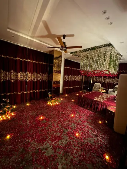 The room viewed from the entrance, showing the path of candles leading into the space, which is filled with rose petals and beautiful floral arrangements.