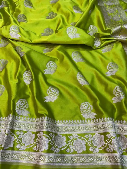 This lime green Banarasi saree is a modern take on a traditional weave. The silver rose motifs are scattered across the body, and the border features a detailed floral vine pattern.