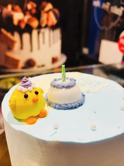 A close-up of a cute fondant chick and a mini birthday cake, perfect as toppers for a larger cake.