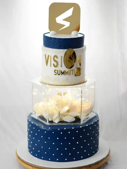 I also create cakes for corporate events. This three-tier cake for a "Vision Summit" features the company logo, a revolving top tier, and a sophisticated blue and white design.