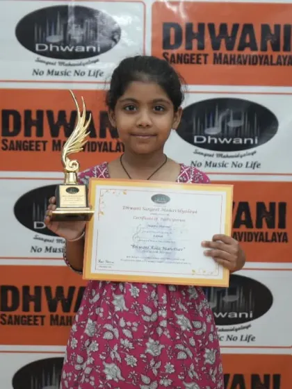 A young student proudly displays her certificate and trophy.