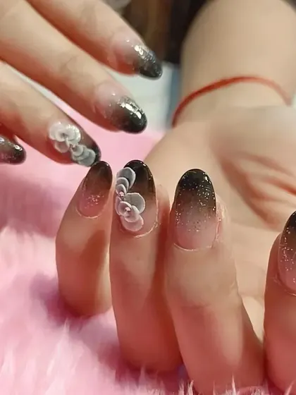 A chic and moody take on 3D florals. This design features a black glitter ombré on a natural base, accented with delicate, sculpted grey flowers for a sophisticated contrast.
