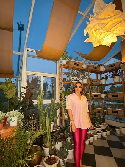 Posing in a greenhouse, this outfit feels both edgy and natural. The pop of pink from the leggings against the lush green background creates a beautiful visual contrast.