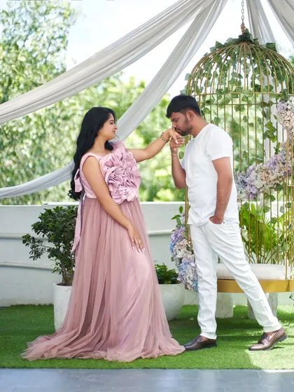 A classic, chivalrous pose that looks straight out of a storybook. The soft pink of the 'Bloom' gown adds to the romantic atmosphere of this maternity shoot.