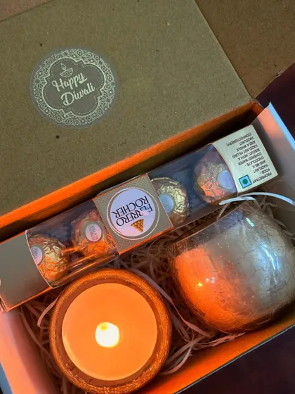 A thoughtful mini hamper for Diwali. This box contains a set of two scented candles in glass jars, Ferrero Rocher chocolates, and a Diwali message card.