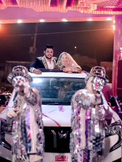 A full view of the wedding exit celebration, capturing the dancers, the car, and the happy couple in one festive frame.