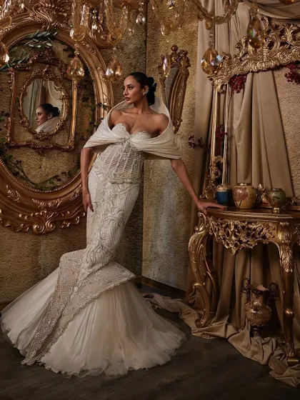 An ivory gown that celebrates contrast. The fit-and-flare silhouette is sculpted with a corseted bodice and finished with a dramatic hooded panel, creating a look that is elegant, intentional, and unforgettable.