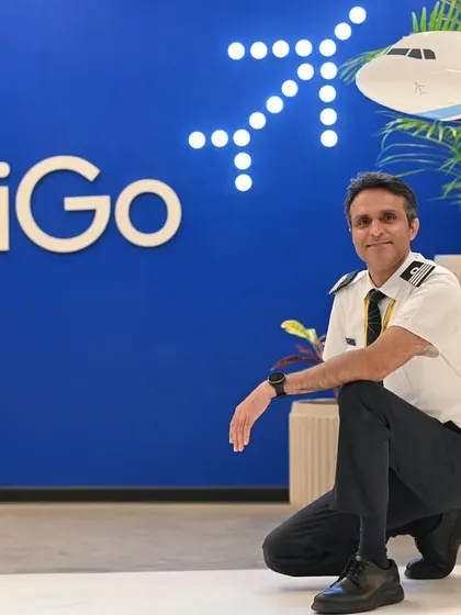A wide shot of an IndiGo pilot in front of the company's logo. This is a classic corporate branding shot that is bold and effective.