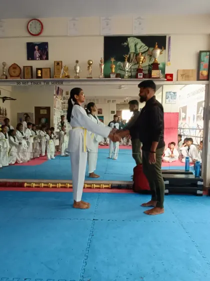 A student receives her yellow and green belt.
