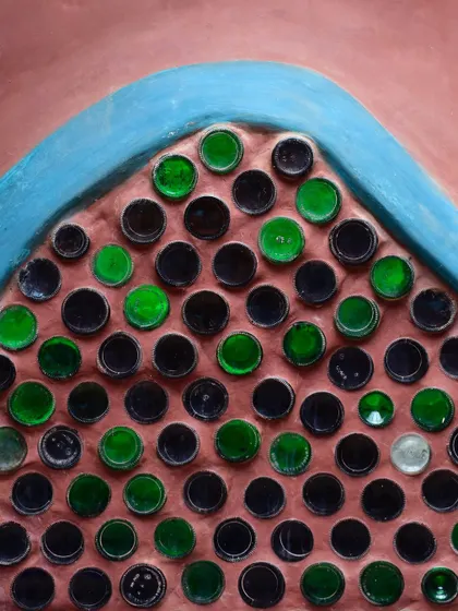 A vibrant bottle wall, where recycled glass bottles are used as masonry units. This technique allows natural light to filter through, creating colorful patterns while upcycling waste.
