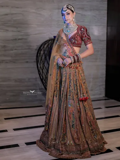A full-length shot with dramatic blue backlighting, creating a cool contrast with the warm tones of the bride's lehenga. This showcases our ability to play with colored lighting for unique effects.