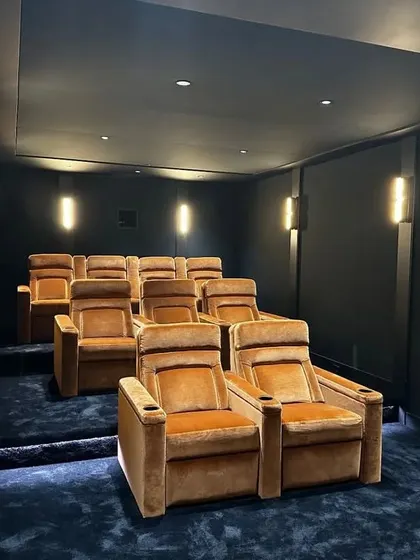 A slightly different angle of this elegant theater, showing the warm wall sconces that provide soft, ambient light without creating glare on the screen.