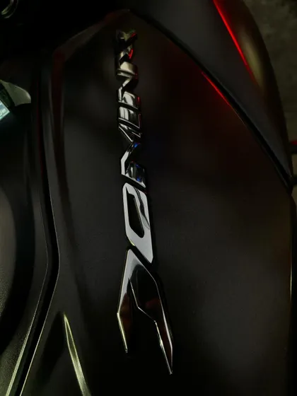 A close-up shot of the Dominar logo on the tank, captured in the ambient light of traffic.
