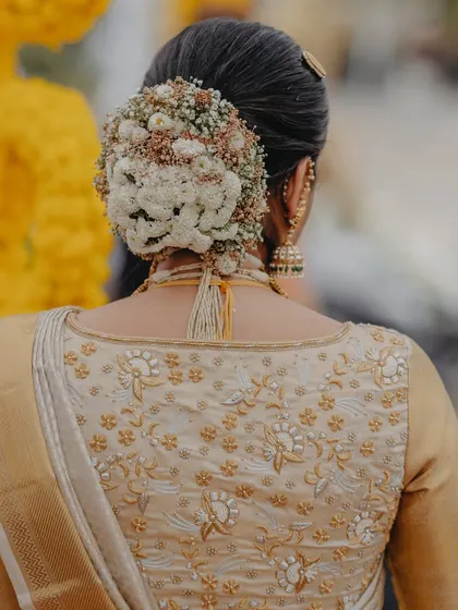 A beautiful shot of a floral bridal bun. This style is perfect for receptions or for brides who prefer an updo. You'll learn how to create these elegant, flower-adorned buns.