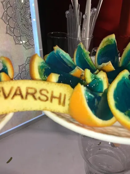 I love adding personal touches to your event. Here, I've created custom edible garnishes with the wedding hashtag and served colorful jello shots in orange wedges for a unique presentation.