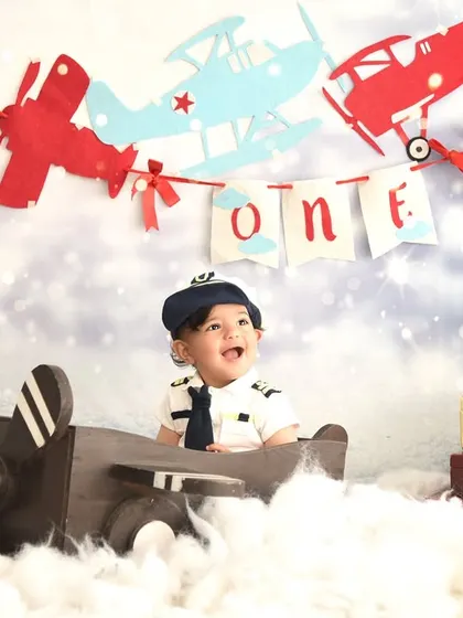 Adventure awaits! This little pilot is ready to fly high for his first birthday. The airplane theme, complete with clouds and a vintage plane, is perfect for a budding explorer.
