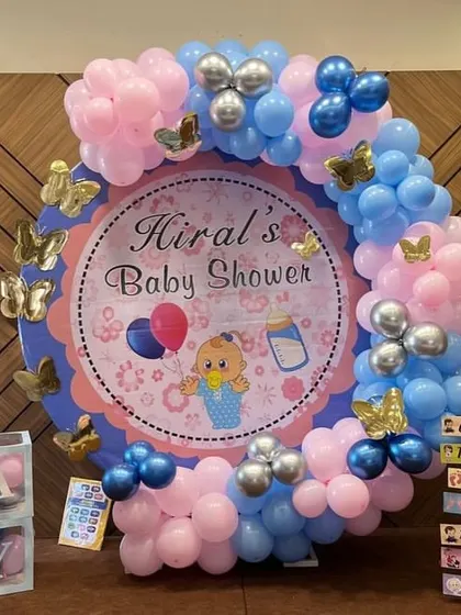 A close-up of the baby shower setup, showing the custom printed backdrop and the butterfly accents on the balloon arch.
