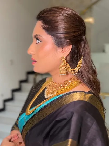 A chic and sophisticated look with a black and blue silk saree. The hair is styled in a simple yet elegant half-updo with soft waves, perfect for a formal evening event.