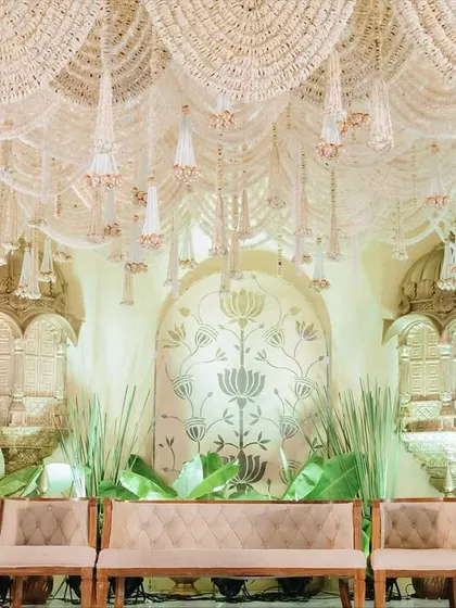 The full stage setup for the 'Whispering Willows' theme, with elegant seating arranged before the ornate jharokha backdrop. The design is balanced, grand, and steeped in cultural richness.