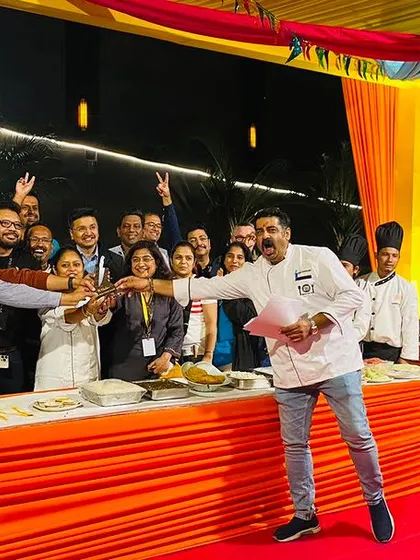 A team excitedly presents their dish to the judges at the corporate cook-off. The vibrant outdoor setting and colorful decor add to the fun and festive atmosphere of the team-building event.