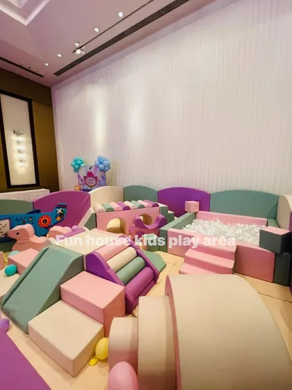 A full view of a large pastel play area setup indoors, featuring a ball pit, bridge, slides, and rockers.