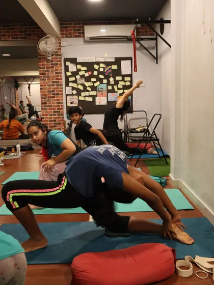 Partner work can be a fun way to explore deeper stretches. Here, one student supports another in a challenging backbend variation.