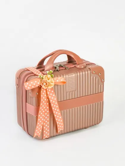 A product shot of a rose gold mini-suitcase used as a gift box. The clean white background and elegant ribbon make it look like a premium and unique packaging option.