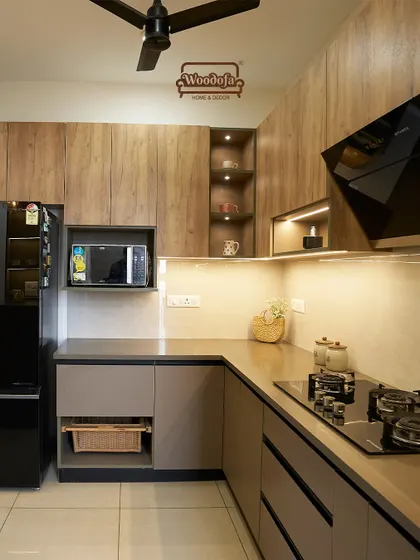 This kitchen combines warm wood-finish upper cabinets with neutral grey lower cabinets. The open niche with lighting is perfect for displaying decorative items.